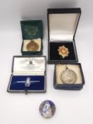 A collection of medals and badges, including two theatre medals, an enamelled coin brooch (enamel