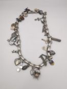 A Victorian silver fancy link charm necklace with various charms, including enamel shields, a silver