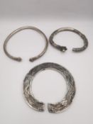 Three white metal (tested as silver) tribal design bangles, including a flat bangle with etched