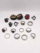 A collection of sixteen silver rings of various designs, including a carved cinnabar lacquer dress