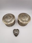 A collection of three silver and white metal boxes. Two Indian repousse circular boxes decorated