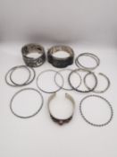 A collection of thirteen white metal and silver bangles, including an Indian coral set cuff