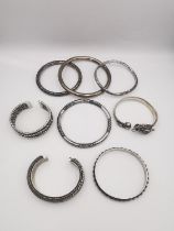 Eight silver bangles, including a Chinese dragon form bangle set with turquoise, a plaited design