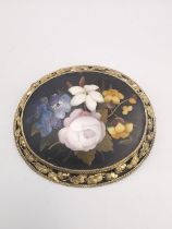 A 19th century grand tour Italian Pietra Dura brooch. The oval panel with a pale pink rose, white