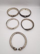 A collection of five white metal (tests as silver) tribal bangles, a pair of coiled snake form
