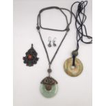 A collection of Chinese jewellery, including a jade Bi disc pendant, a silver and coral fish pendant
