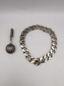 A silver napkin holder with shell nips along with a silver chain curb link bracelet with safety
