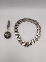 A silver napkin holder with shell nips along with a silver chain curb link bracelet with safety