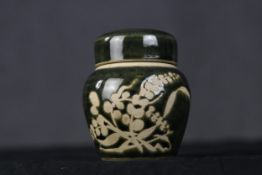 A Japanese ceramic lidded pot with deep green glaze and floral decoration. H.10 x W.9 x D.9 cm.