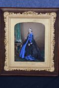 An overpainted photograph of Queen Victoria standing by a basket of flowers. Circa 1870. In a