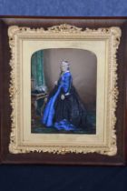 An overpainted photograph of Queen Victoria standing by a basket of flowers. Circa 1870. In a