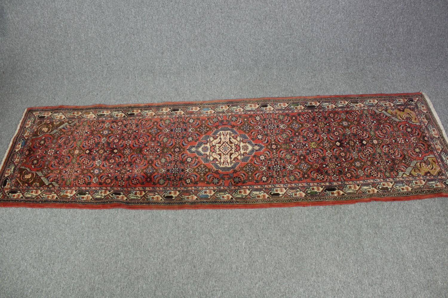 Runner, Heriz with central stylised floral medallion on a salmon ground. L.280 W.80cm.