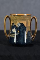 A double handled Royal Doulton tankard designed by Charles Noke. Depicting a monk and fishmonger.