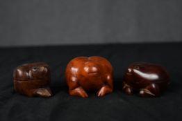 A set of three carved hardwood lidded pots in the shape of frogs. Twentieth century. H.4 x W.5.5 x