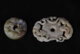 Two Chinese bi disks made of jade and soapstone. The jade design features what looks like tigers and
