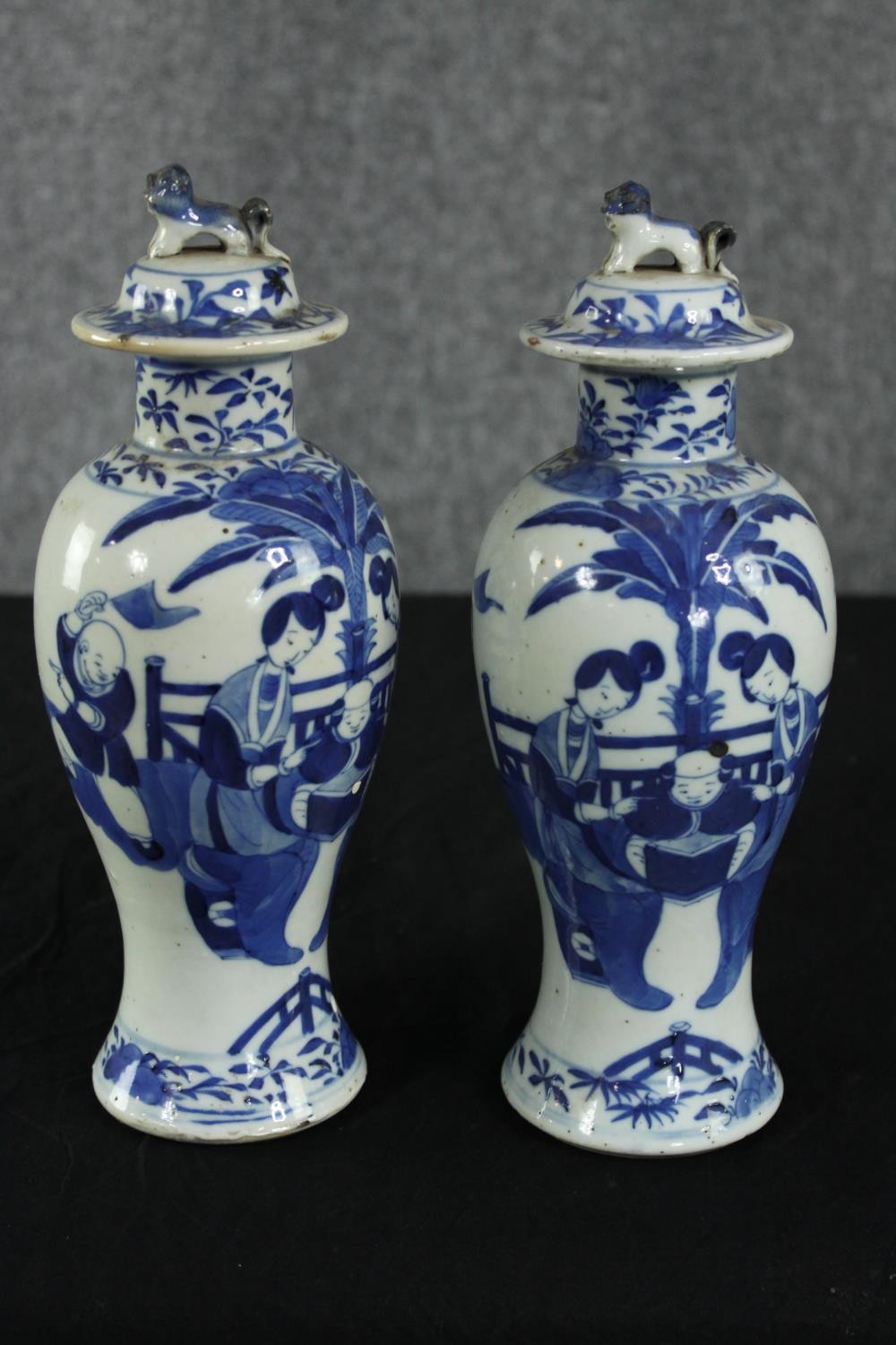 A pair of 19th century Chinese hand painted porcelain lidded urns. The lid finials in the form of