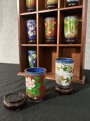 A twelve piece set of Chinese cloisonne enamel floral design tea cups. Each on a wooden stand and