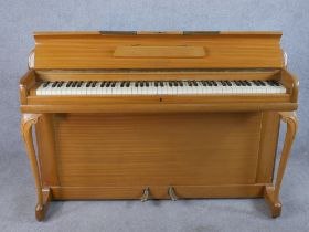 A mid 20th century Kimble beech upright piano raised on carved cabriole supports terminating on