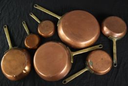 A set of seven early 20th century copper and brass graduated frying pans. Dia.24cm. (largest)