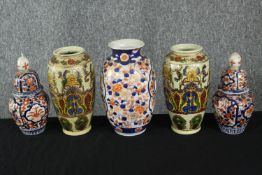 A pair of Japanese Imari ware lidded urns decorated with a stylised floral design along with a