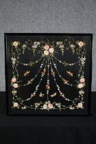 A framed embroidery. An intricate floral design on a black background. Framed and glazed. H.53 W.