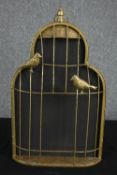 A decorative metal birdcage. With two birds perched on the outside. The cage very likely once