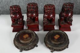 Four Chinese red resin Foo dogs along with a pair of carved and pierced Chinese hardwood stands. H.