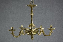 A heavy French brass chandelier with five branches of lights and floral decoration throughout.