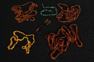 Four knotted amber pebble necklaces, one opaque along with two Art Deco Bakelite hat pins and a