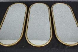 A set of three gilt metal mirrors. H.52 W.21cm. (each)