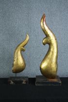 Two carved abstract modern sculptures painted in gold resting on wooden plinths. H.89cm. (largest)
