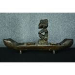 A large carved wooden canoe with a serene looking seated figure. H.39 W.80 cm.