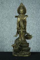 A brass Chinese Buddha standing on a coiled serpent or dragon. The plinth has been weighted. The