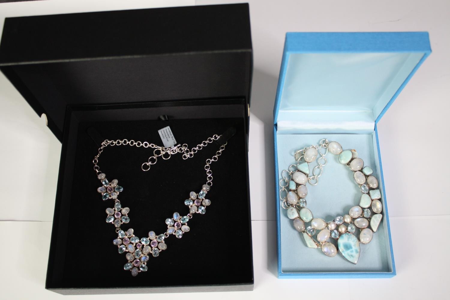 Two boxed statement articulated silver and gemstone necklaces. One of a floral design set with