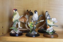 A collection of four hand painted birds and a dog.