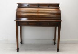 A Georgian style mahogany cylinder top desk with tambour shutter enclosing a fitted interior on