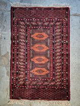 A small Eastern rug with repeating lozenge medallions on a madder field within multiple geometric