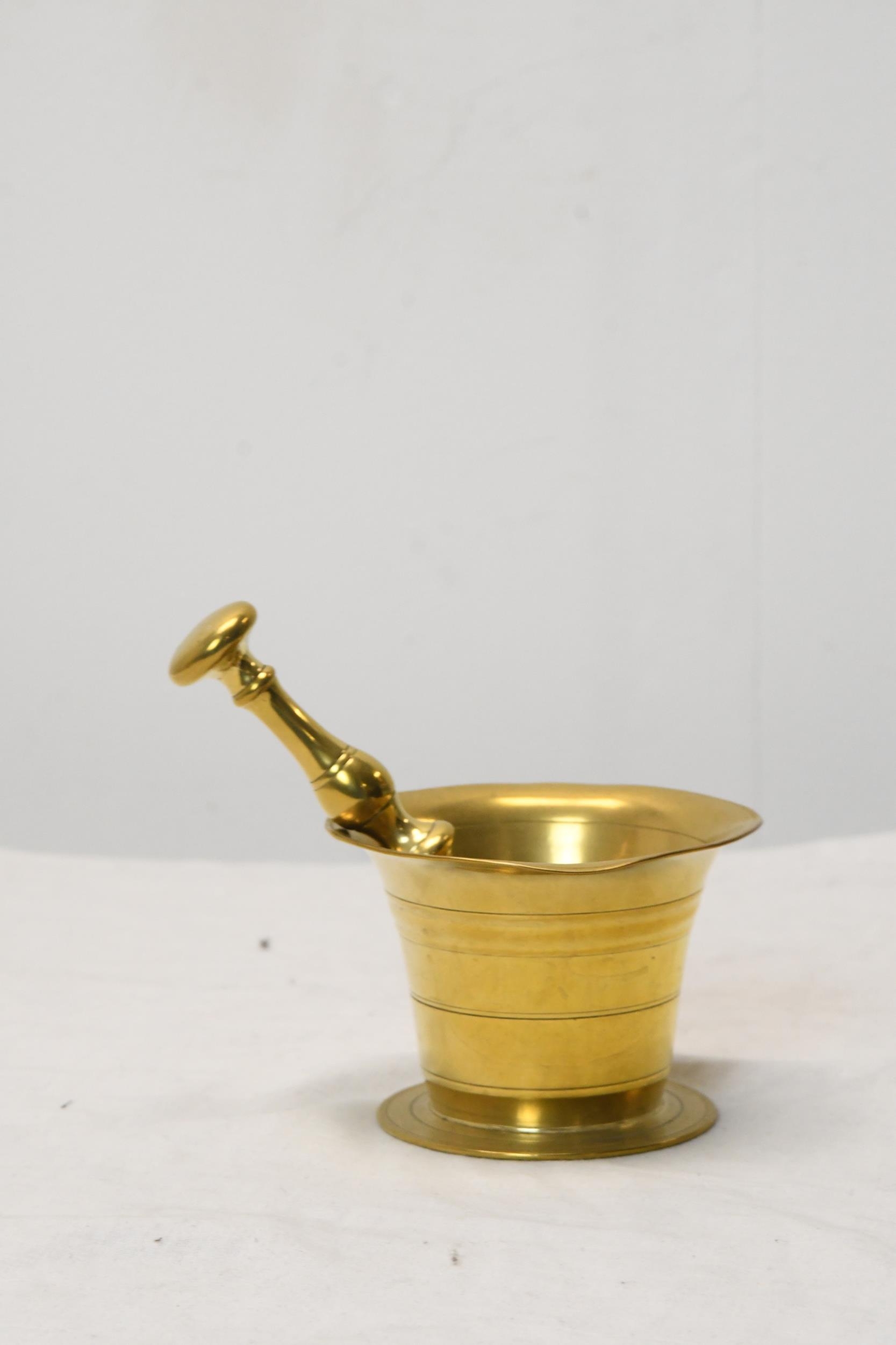 An early 20th century brass pestle and mortar. Pestle is 16cm long, mortar is H.8 W.10 D.10cm.