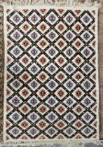 A woollen carpet with allover geometric pattern on an ivory field. L.230 W.195cm.