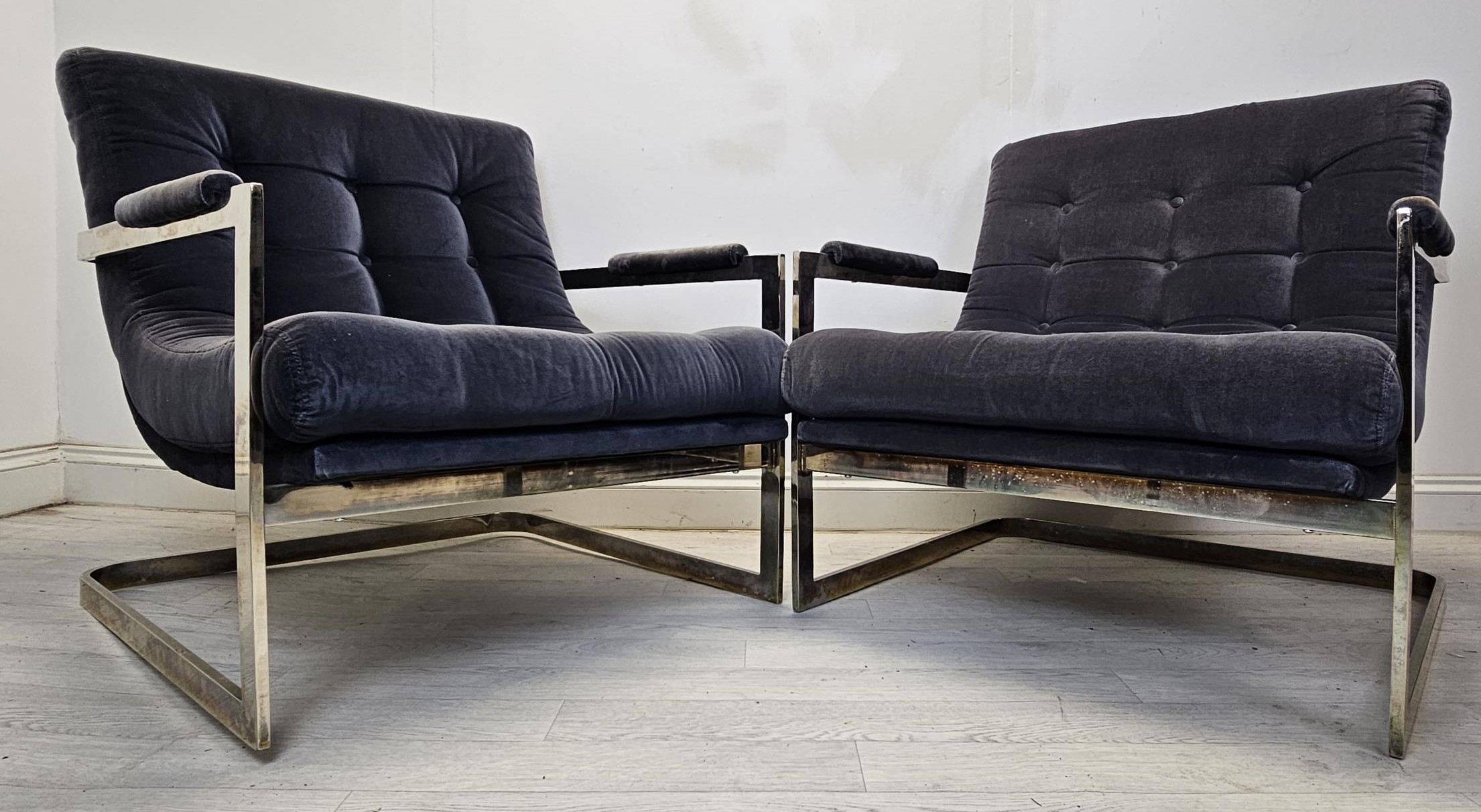 Lounge armchairs, buttoned upholstery on metal cantilever frames. H.87 W.80 D.77cm.