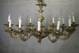 A large twelve branch heavy brass chandelier with scrolling foliate design. French. Oval form. H.