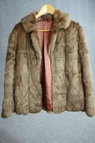 A brown fur short winter coat with pink silk interior. Label to the inside.