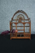 A decorative wooden birdcage with metal bars and a feathered bird. H.42 W.31 D.21 cm.