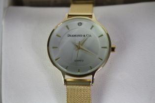 A boxed Diamond and Co ladies quartz watch with gold tone mesh strap and white dial. Box and papers.