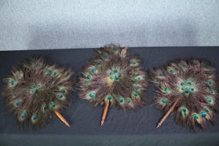 Three peacock feather fans with turned handles L.60cm. (each)