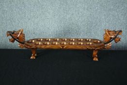 A hardwood decorative Mancala game board in the shape of a dragon. With carved decoration and