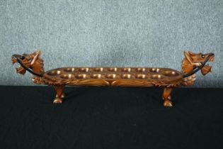 A hardwood decorative Mancala game board in the shape of a dragon. With carved decoration and