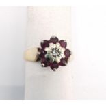 A pink metal (tests as 9ct) ruby and diamond cluster ring. Ring set to centre with a round eight cut