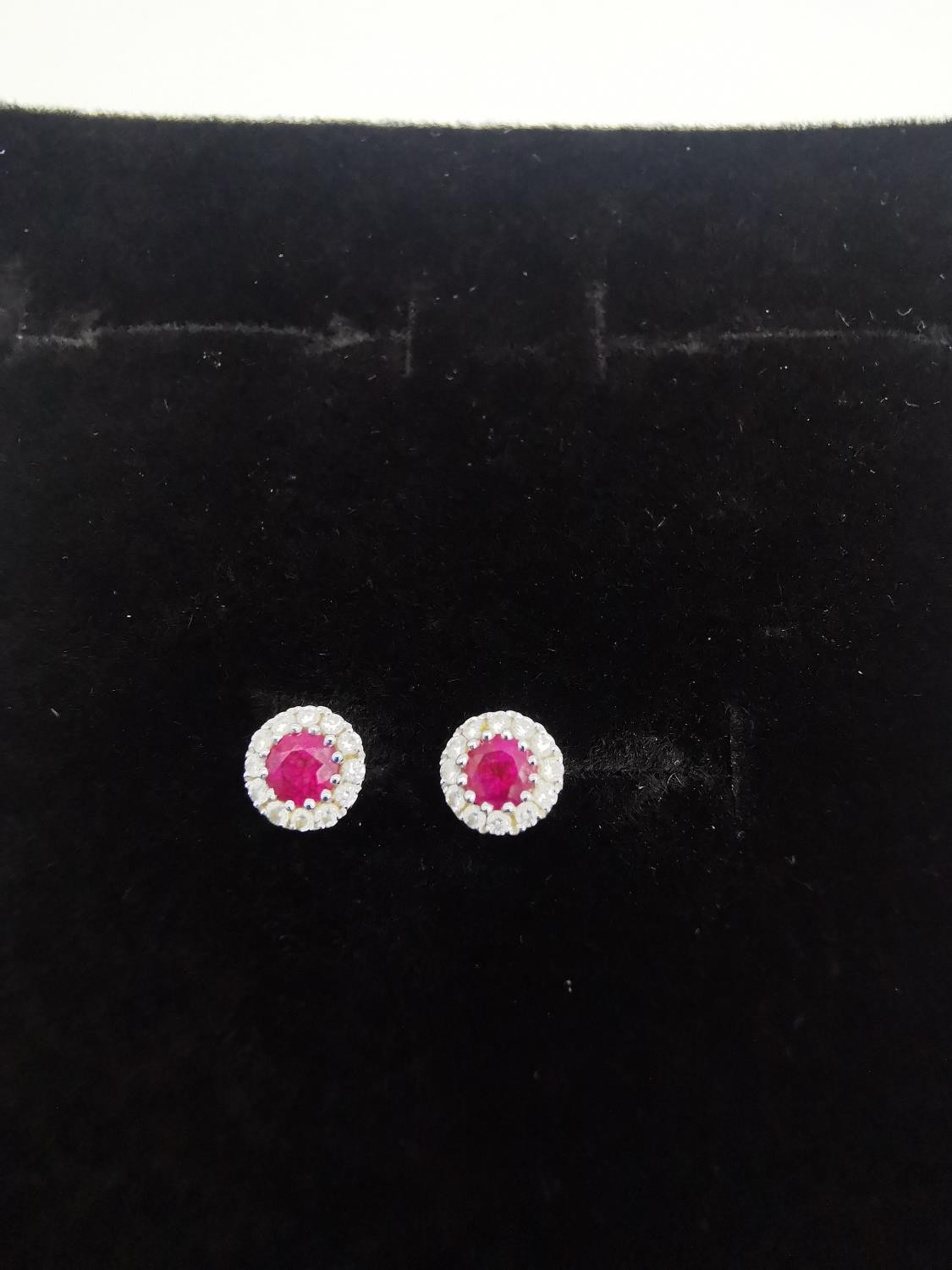 A pair of 18ct white gold ruby and diamond cluster stud earrings. Each set to centre with a round