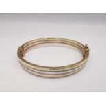 A modern 9ct three colour gold hinged bangle. The bangle comprised of three bands, white, rose and